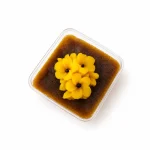 شات تشریفاتی حلوا زعفران و هل در ظرف شفاف درب‌دار همراه قاشق و تزئین گل حلوا یاسوج